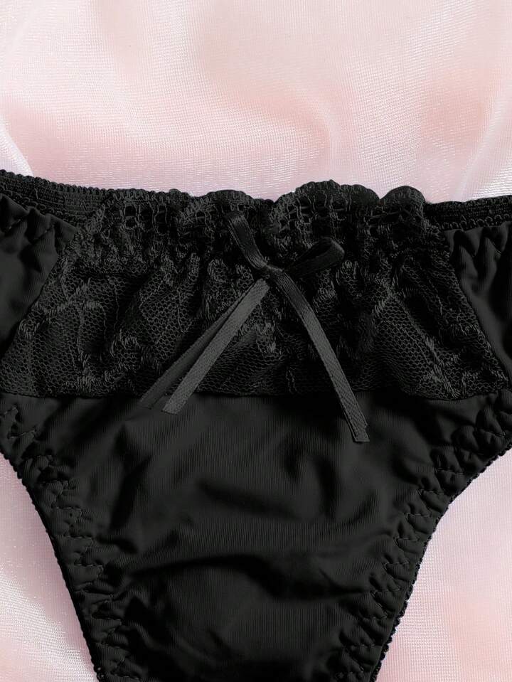 Black lace-trimmed underwear on a light pink background