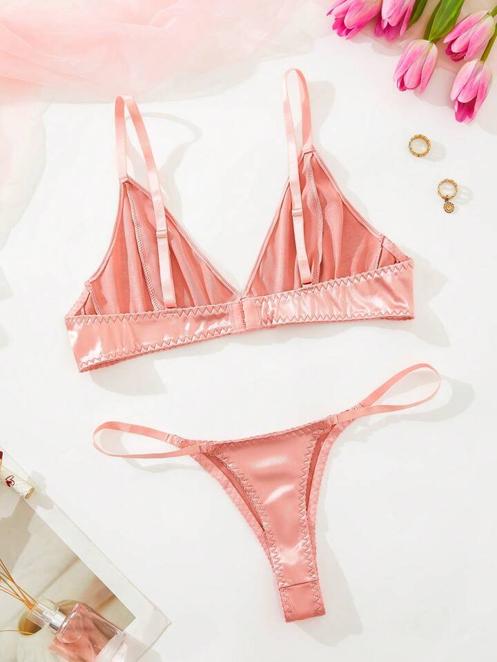 Pink bra and panty set on a white surface with pink tulips and gold jewelry.