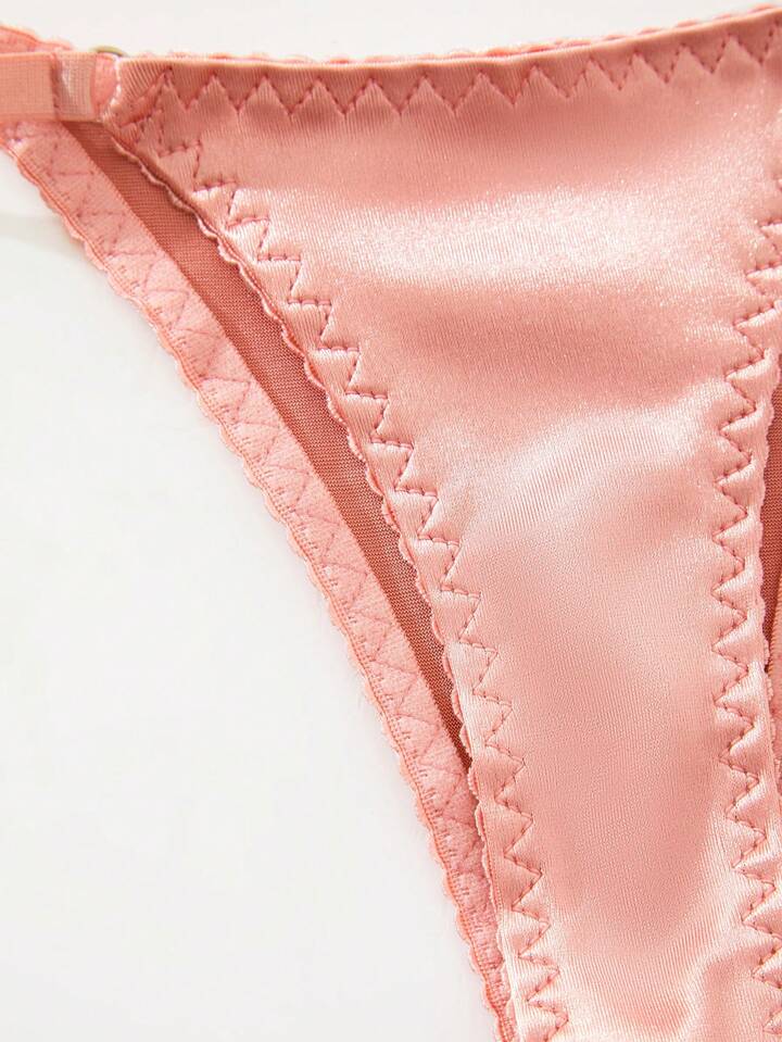 Close-up of pink satin fabric thong with a white background