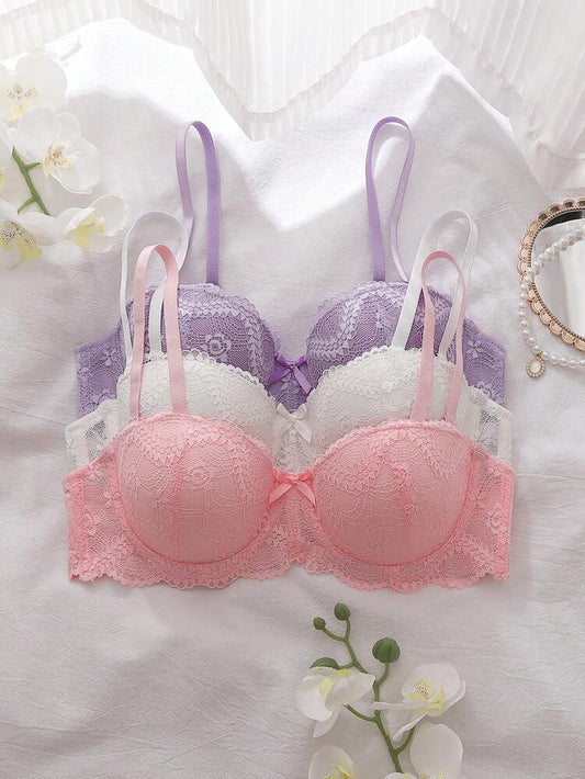 Pink and white lace bra on a light background with flowers and jewelry.