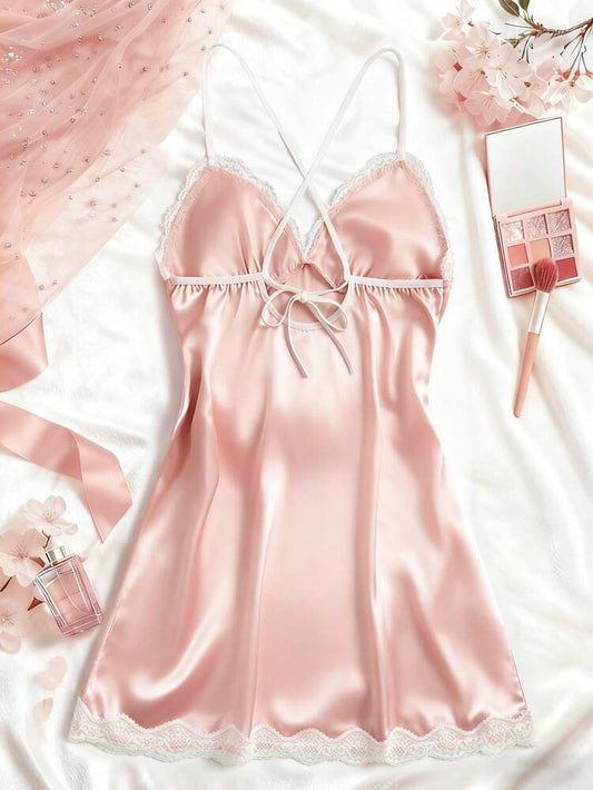 Pink satin nightgown with floral decorations and makeup items on a white background