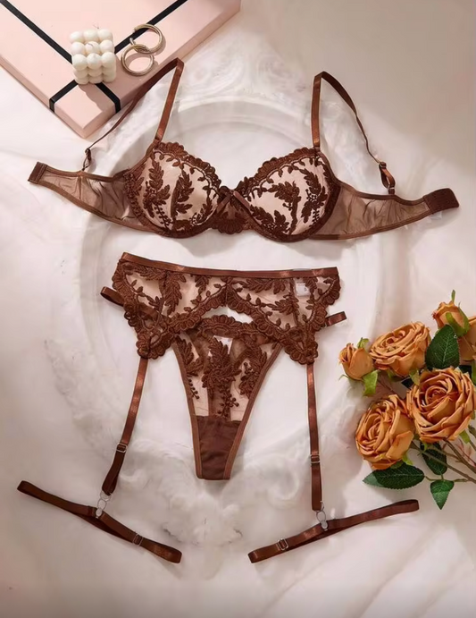 A three-piece brown lace lingerie set laid flat on a white fabric background, featuring a bra, matching panties, and garter straps.