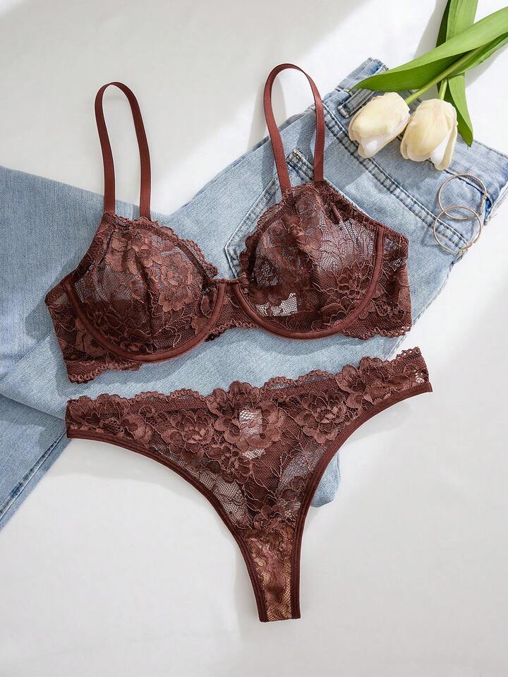 Brown lace lingerie set on a white surface with denim jeans and tulips in the background.