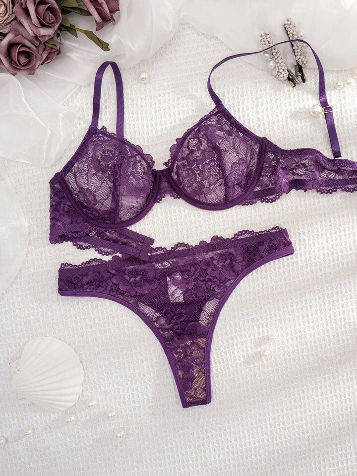 Purple lace lingerie set on a white surface with flowers and pearls.