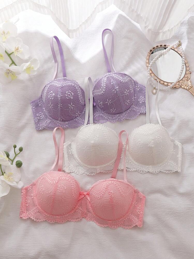 Set of three lace bras in purple, white, and pink on a light background.