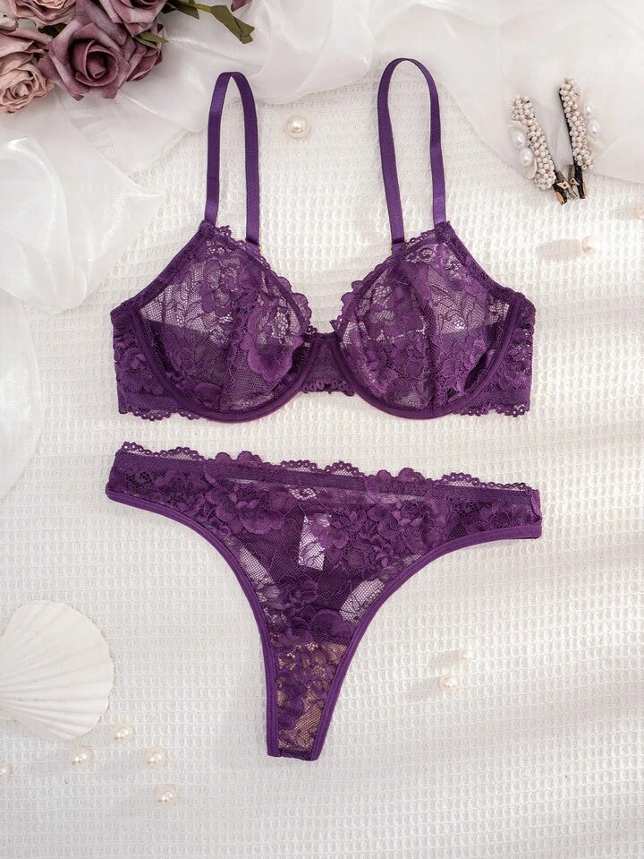 Purple lace lingerie set on a textured white surface with flowers and jewelry.