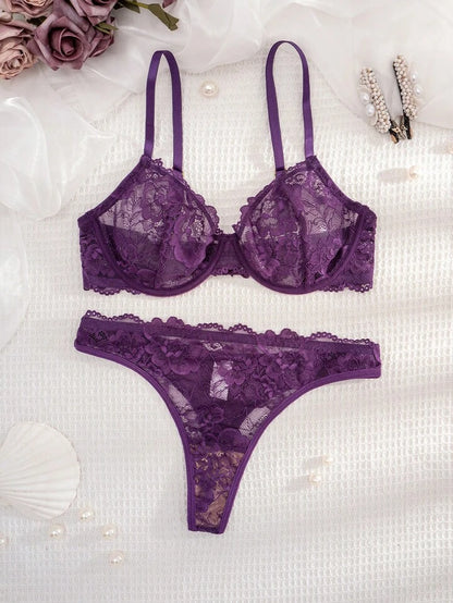 Purple lace lingerie set on a textured white surface with flowers and jewelry.