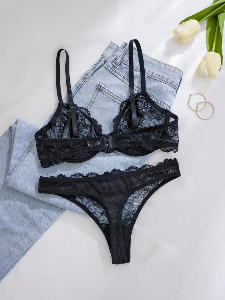 Black lace lingerie set with denim jeans and tulips on a light surface
