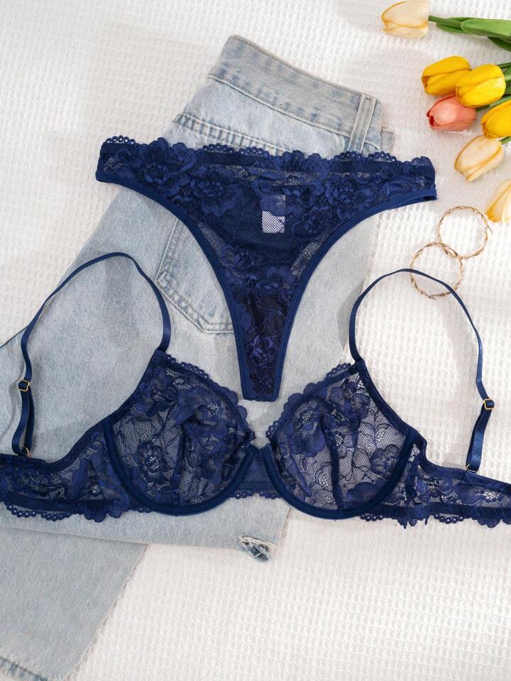 Navy blue lace bra and panties set on a white surface with denim and tulips.