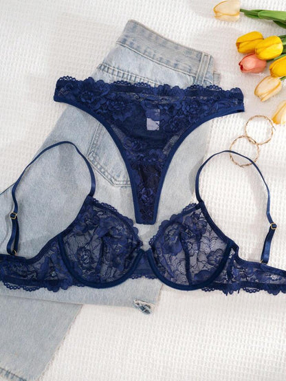 Navy blue lace bra and panties set on a white surface with denim and tulips.