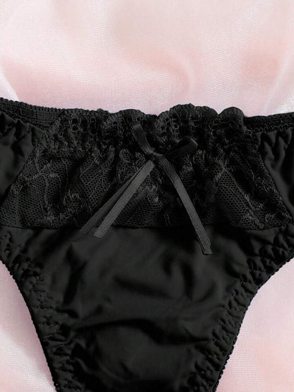 Black lace-trimmed underwear on a light pink background