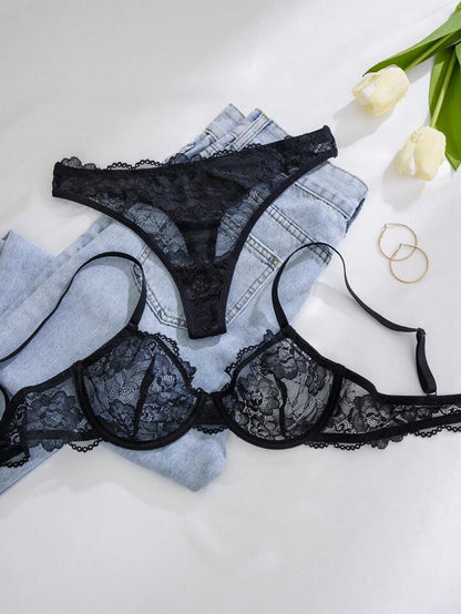 Black lace lingerie set on a white surface with tulips and jewelry.
