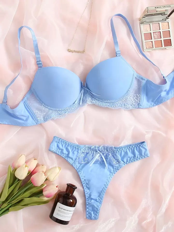 Blue lingerie set with flowers and a bottle on a pink background