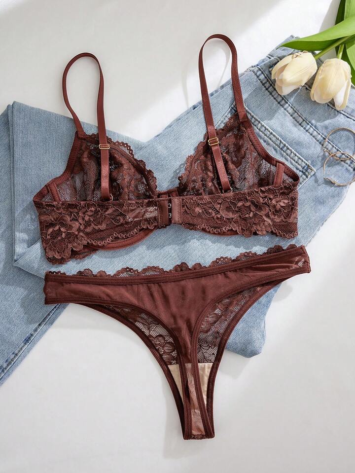 Brown lace lingerie set on a white surface with denim fabric and tulips in the background
