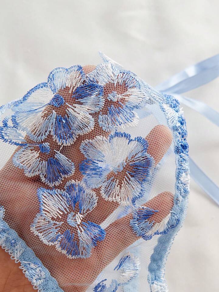 Blue floral embroidery on a sheer fabric background