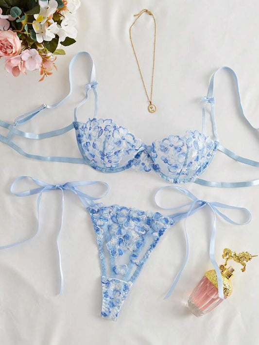Blue floral lingerie set on a white background with flowers and a necklace.