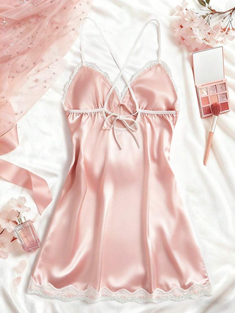 Pink satin nightgown with floral decorations and makeup items on a white background