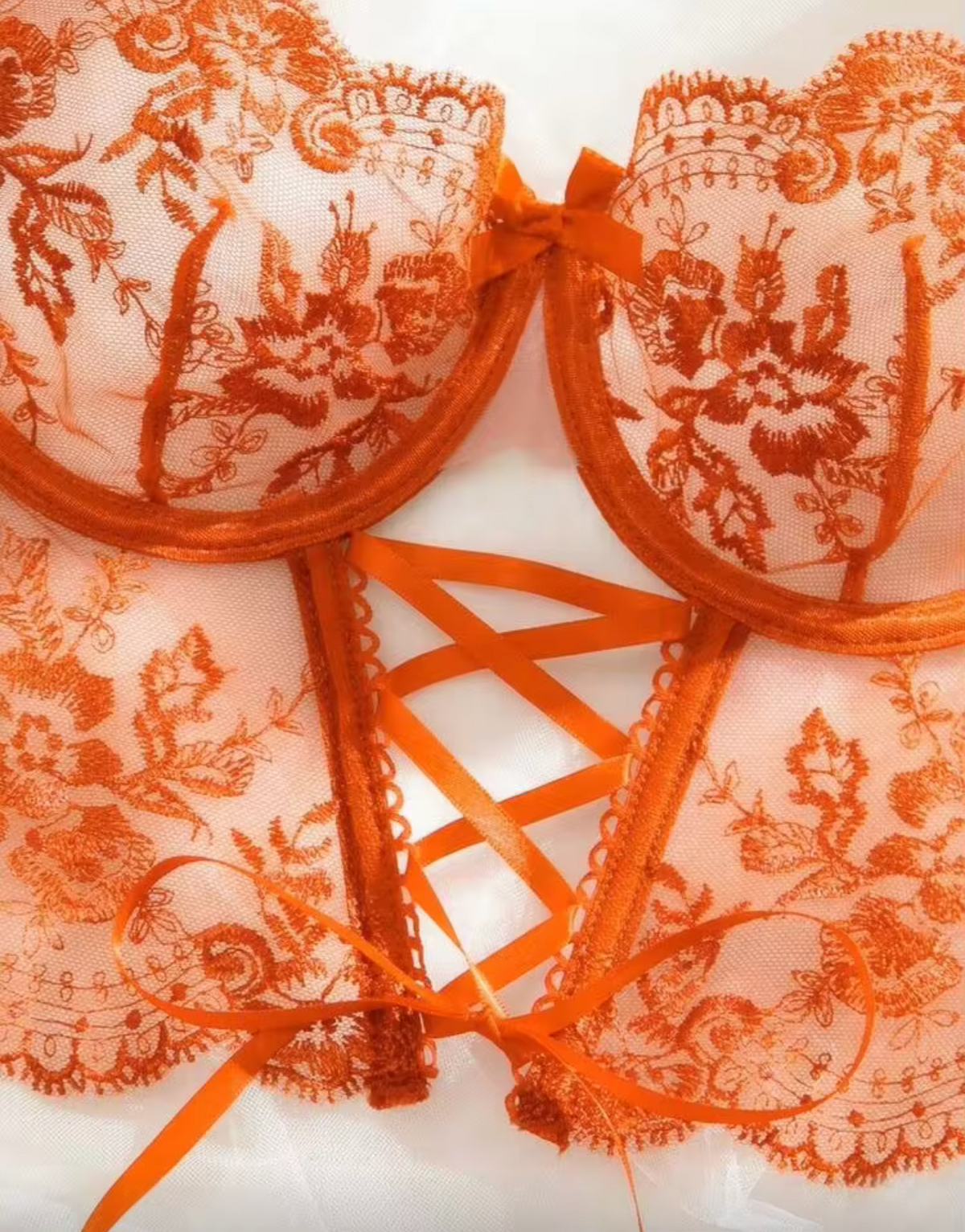 An orange lace and mesh lingerie bustier set with intricate floral embroidery, orange lace trim, and a strappy corset-style front panel, shown on a white background.