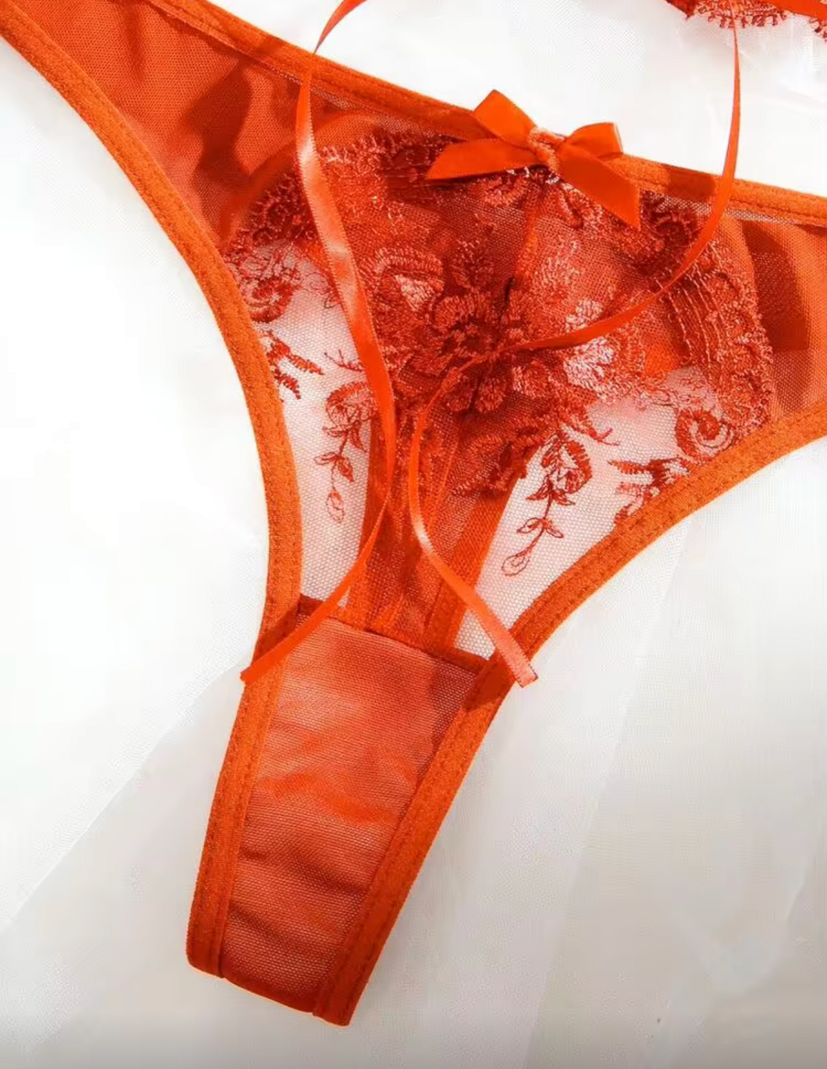 An orange sheer lace thong with a matching bow, displayed on a white background perfect for halloween  or fall autumn lingerie