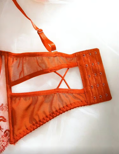 An orange sheer mesh lingerie underwire cup with a cutout and side grommets, shown on a white background.